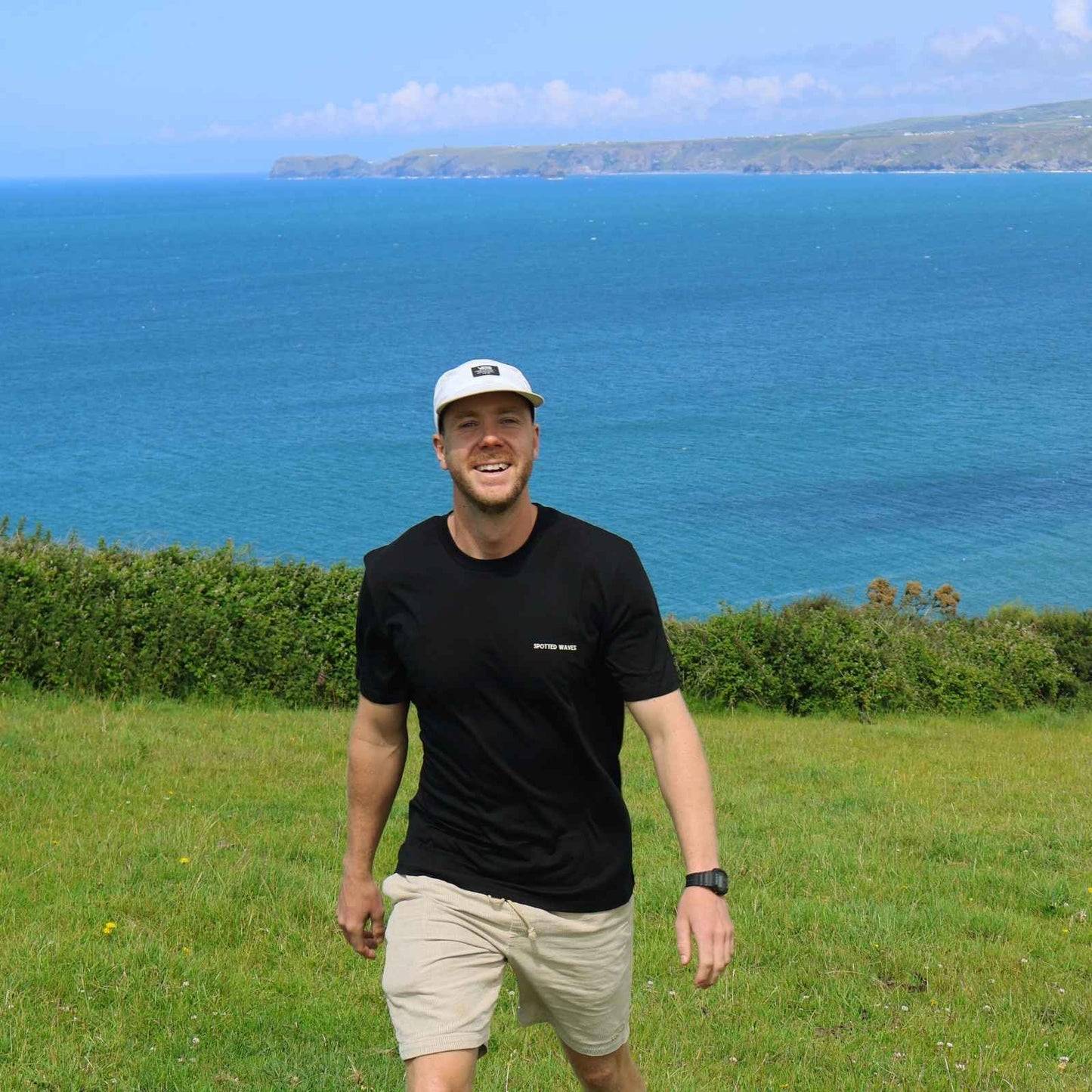 Man standing in a grassy field with a scenic ocean view