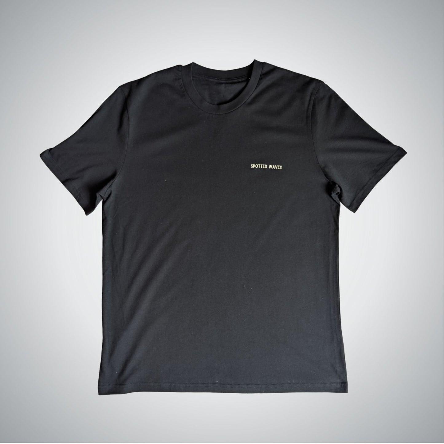 Black t-shirt with a small logo on a light gray background