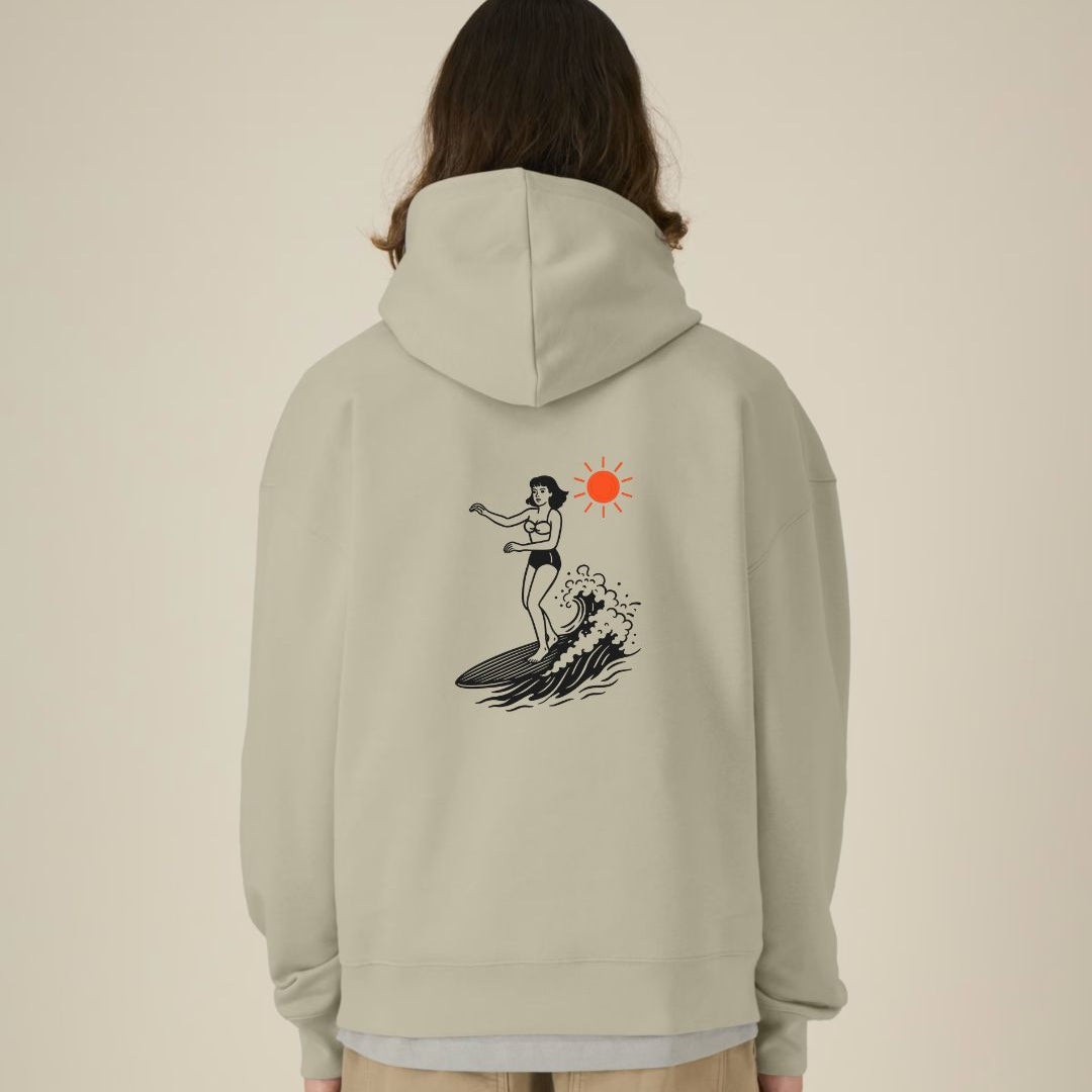 Person wearing a light gray hoodie with a graphic design on the back against a beige background