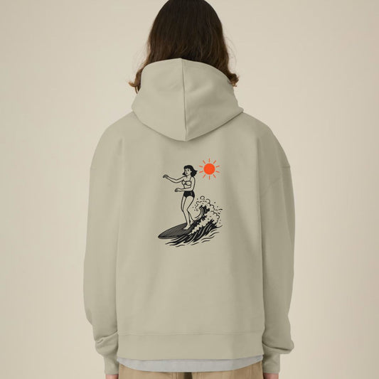 Person wearing a light gray hoodie with a graphic design on the back against a beige background