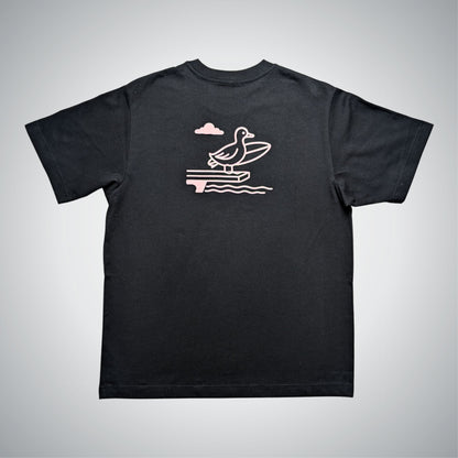 Black t-shirt with a pink graphic of a duck on a jumping board