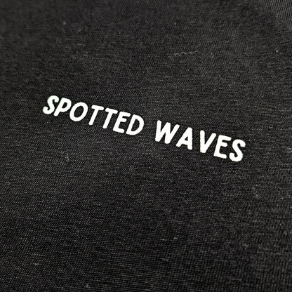 Black fabric with 'SPOTTED WAVES' text embroidered on it