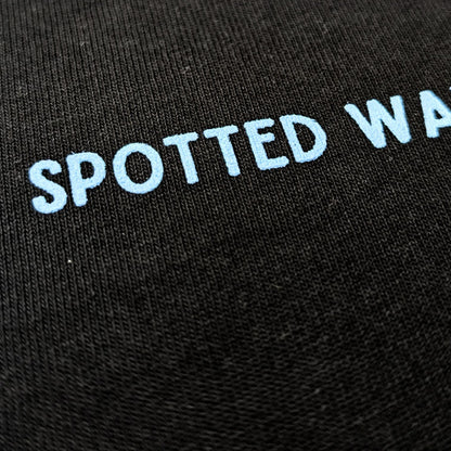 Black fabric with 'SPOTTED WAVES' embroidered in white