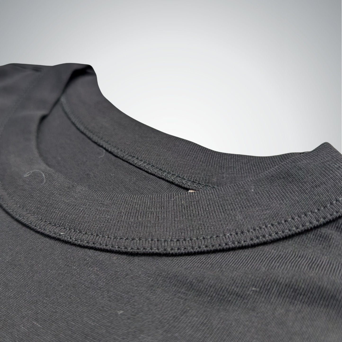 Close-up of a black shirt collar with stitching details on a light gray background